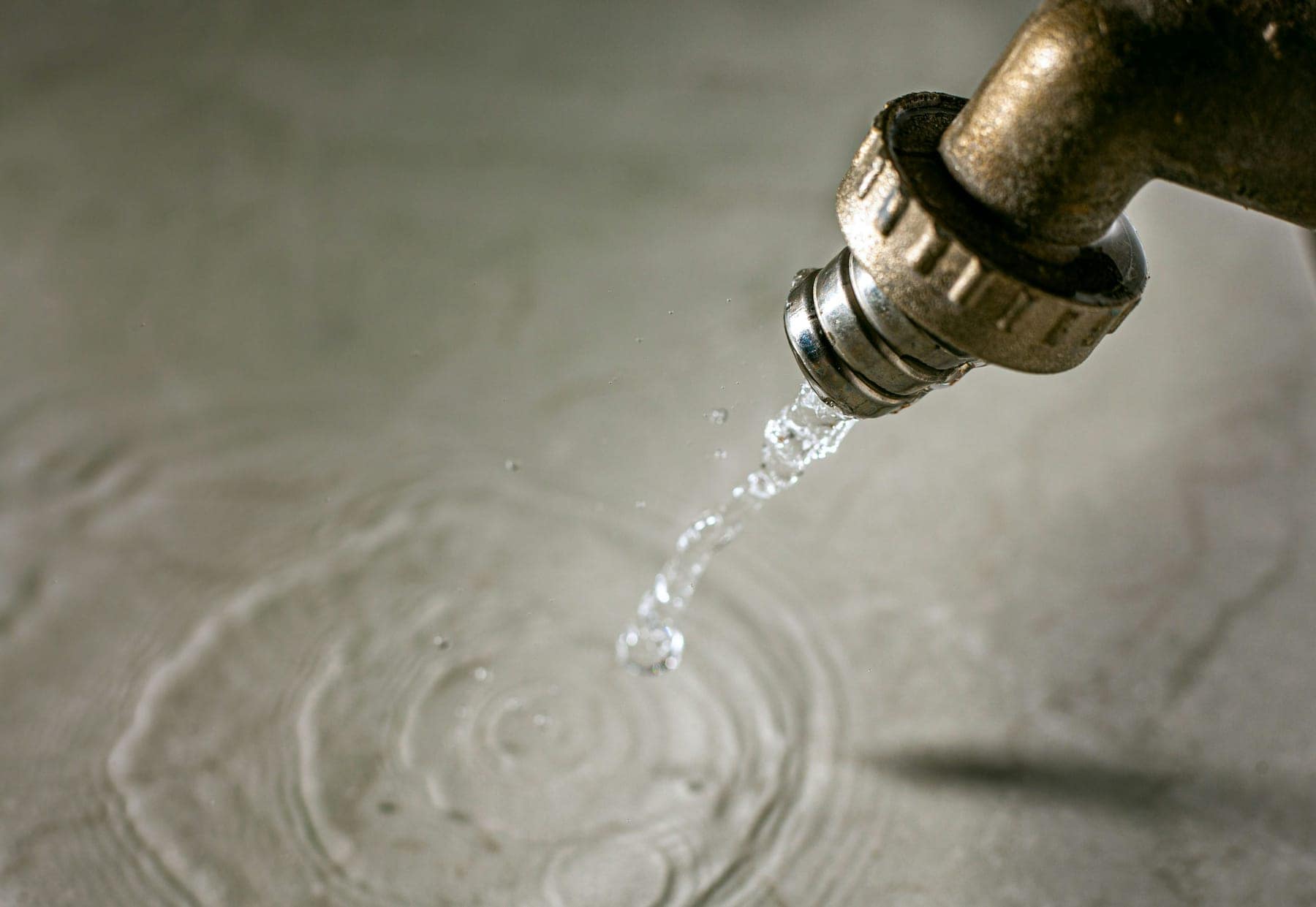 Wasser läuft aus einer Messingarmatur auf den Boden